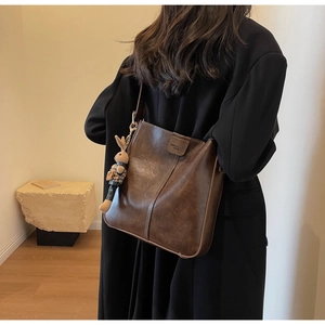 Detail of dark brown vintage bucket bag with leather texture and cute rabbit charm