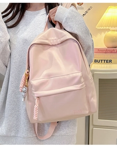 Close-up of pink nylon backpack with front pocket, logo detail and silver bear charm
