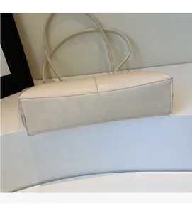 Detail showing the beige tote bag rectangular base and soft leather cylindrical straps