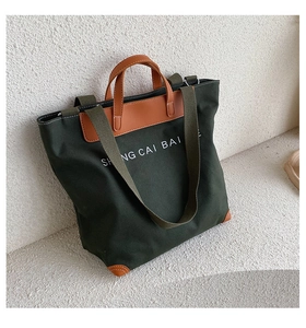 Detail of green canvas tote bag with brown leather corners and adjustable strap