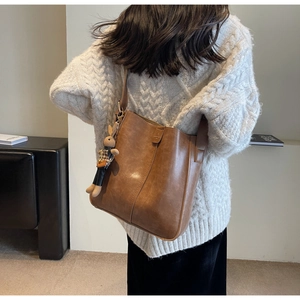 Close-up of brown vintage bucket bag with a cute rabbit doll charm and autumn outfit