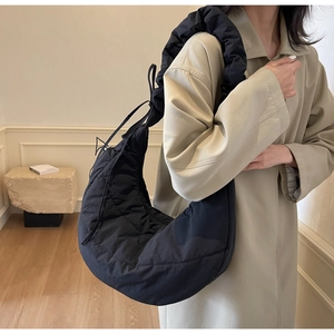 Detail of black quilted puffer crescent bag with stylish ruched shoulder strap design
