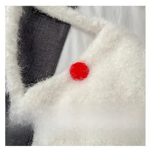 Detail shot of white fuzzy fleece bucket bag featuring a bright red pom-pom accent