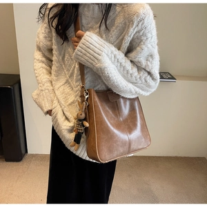 Detail of vintage brown leather bucket bag with a cute rabbit pendant and magnetic flap closure