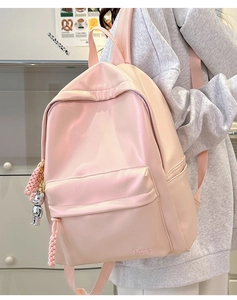 Detail of light pink minimalist backpack with silver bear charm and side pocket