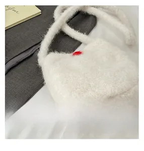 Close-up of fluffy white faux fur bucket bag with a red heart pattern and soft texture