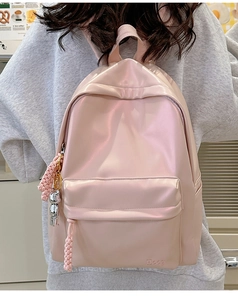 Detail of light pink pearlescent backpack with silver astronaut charm and woven tassel
