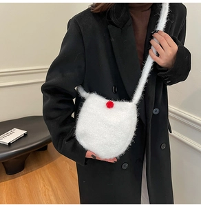 Detail of white plush bucket bag with red ball accent on a black coat background