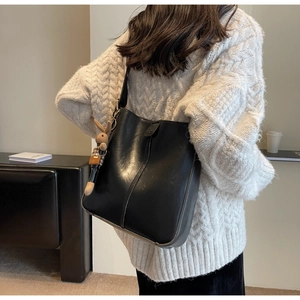 Detail of black PU leather bucket bag featuring a cute brown bunny doll charm