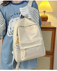 Detail of off-white PU leather backpack featuring side silver bear pendant and logo stamp