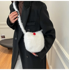Close-up of a white plush bucket bag with a red button detail worn with a black blazer