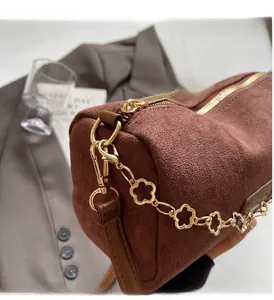 Dettaglio borsa a cilindro in pelle scamosciata marrone con catena dorata floreale