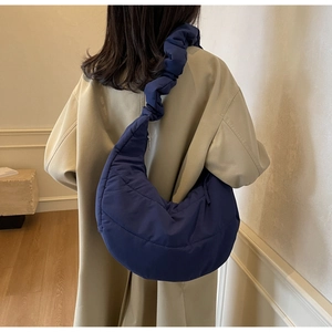 Detail of navy blue quilted crescent bag featuring a stylish scrunchie shoulder strap