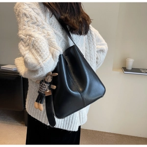 Detail of black bucket bag with textured leather and a cute rabbit charm accessory