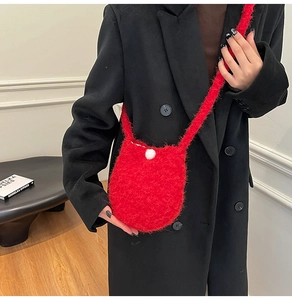 Close-up of red plush bucket bag featuring a soft faux fur texture and round buckle