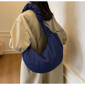 Close-up of a navy quilted puffer hobo bag with unique ruffled shoulder strap details