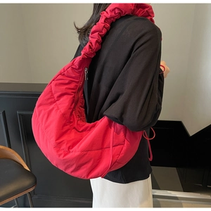 Detail of red quilted nylon bag with ruched bubble shoulder strap and metal zipper