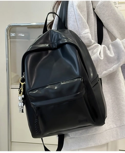 Detail view of black PU leather backpack with Hoog embossing and silver bear keychain charm