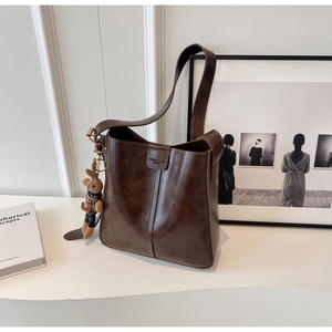 Detail of dark brown vintage leather bucket bag with cute bunny pendant and logo