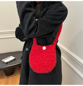 Detailed texture of red plush faux fur shoulder bag featuring white pearl buckle detail