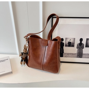 Detail of vintage brown leather bucket bag featuring vertical stitching and rabbit pendant