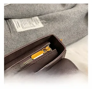 Detailansicht des goldenen Reißverschlusses und der Beschläge der braunen Ledertasche
