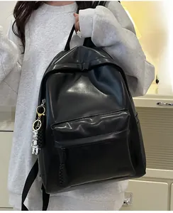 Close-up of black PU leather backpack with a silver robot keychain in a home setting