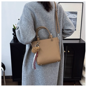 Brown lychee leather tote bag with a cute bear pendant and metal protective base feet