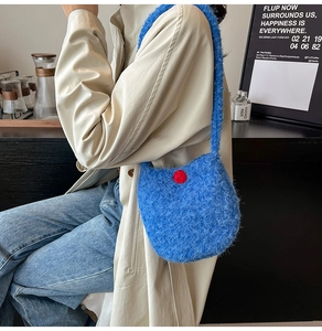 Close-up of blue fleece bucket bag with red button detail worn by a model in a beige coat