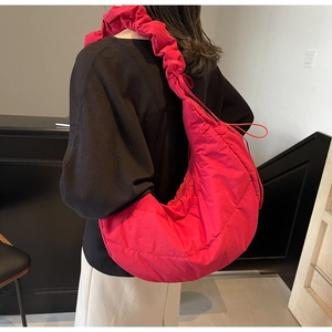 Detail of rose red quilted crescent bag featuring adjustable ruched drawstring straps