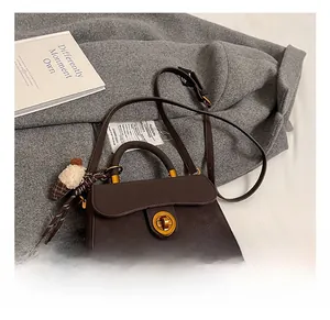 Detailansicht einer braunen Retro-Handtasche mit goldenem Drehverschluss und Plüsch-Anhänger