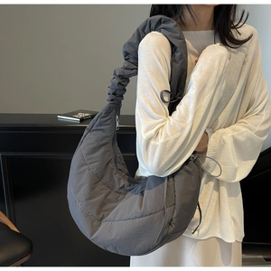 Macro shot of grey quilted nylon fabric with curved stitching and ruched shoulder strap