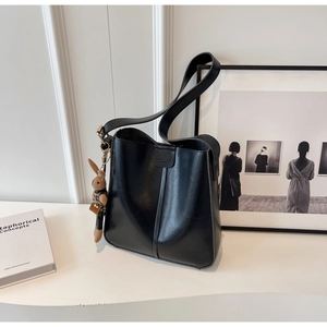 Detail of black leather bucket bag featuring fashion embossing and a cute bunny pendant