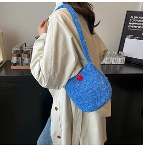 Blue plush bucket bag with red dot detail shown on beige coat for autumn style