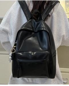 Close-up of black leather backpack featuring silver bear pendant and Hoog logo detail