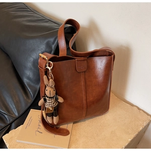 Detail of dark brown vintage leather bucket bag featuring a cute rabbit charm on a stone base