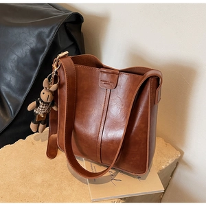 Detail of vintage brown leather bucket bag with cute bunny charm and embossed fashion text