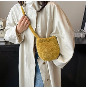 Detail of mustard yellow fuzzy woolen bucket bag texture and shoulder strap on model