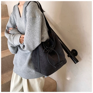 Detail of grey textured hobo bag featuring leather drawstring and woven brand label
