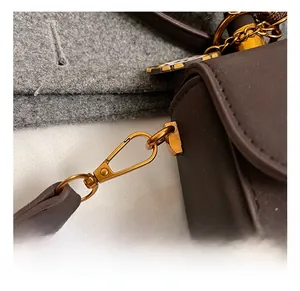 Detail eines hochwertigen Vintage-Gold-Karabinerverschlusses an einer braunen Ledertasche