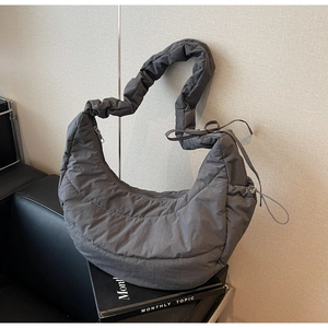 Detail of dark grey quilted puffer hobo bag with ruched strap and side bow design