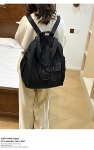 Detail of black nylon backpack showing dual-use handles and large front snap pocket