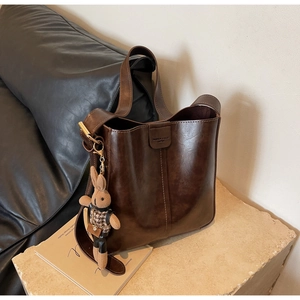 Detail of vintage dark brown leather bucket bag with cute plush rabbit charm on stone base