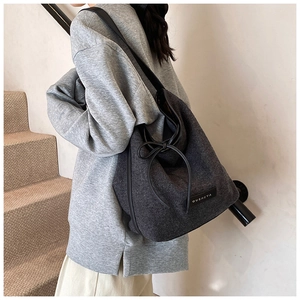 Detail view of dark grey textured canvas tote bag with drawstring bow and brand patch