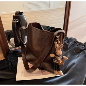 Detailed view of brown leather bucket bag with cute plush rabbit charm and grain texture