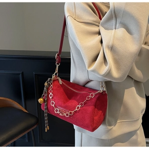Dettaglio borsa Boston in camoscio rosso con catena dorata e ciondolo intrecciato