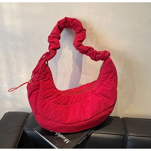 Detail of red quilted puffer moon bag with ruched handle and smooth zipper closure