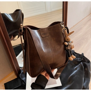 Detail of vintage brown leather tote bag with embossed logo and cute rabbit charm