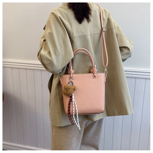 Pink lychee grain leather tote bag with plush bear charm and detachable shoulder strap