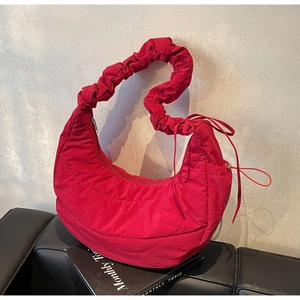 Detail of the ruched shoulder strap and quilted texture on the red nylon handbag